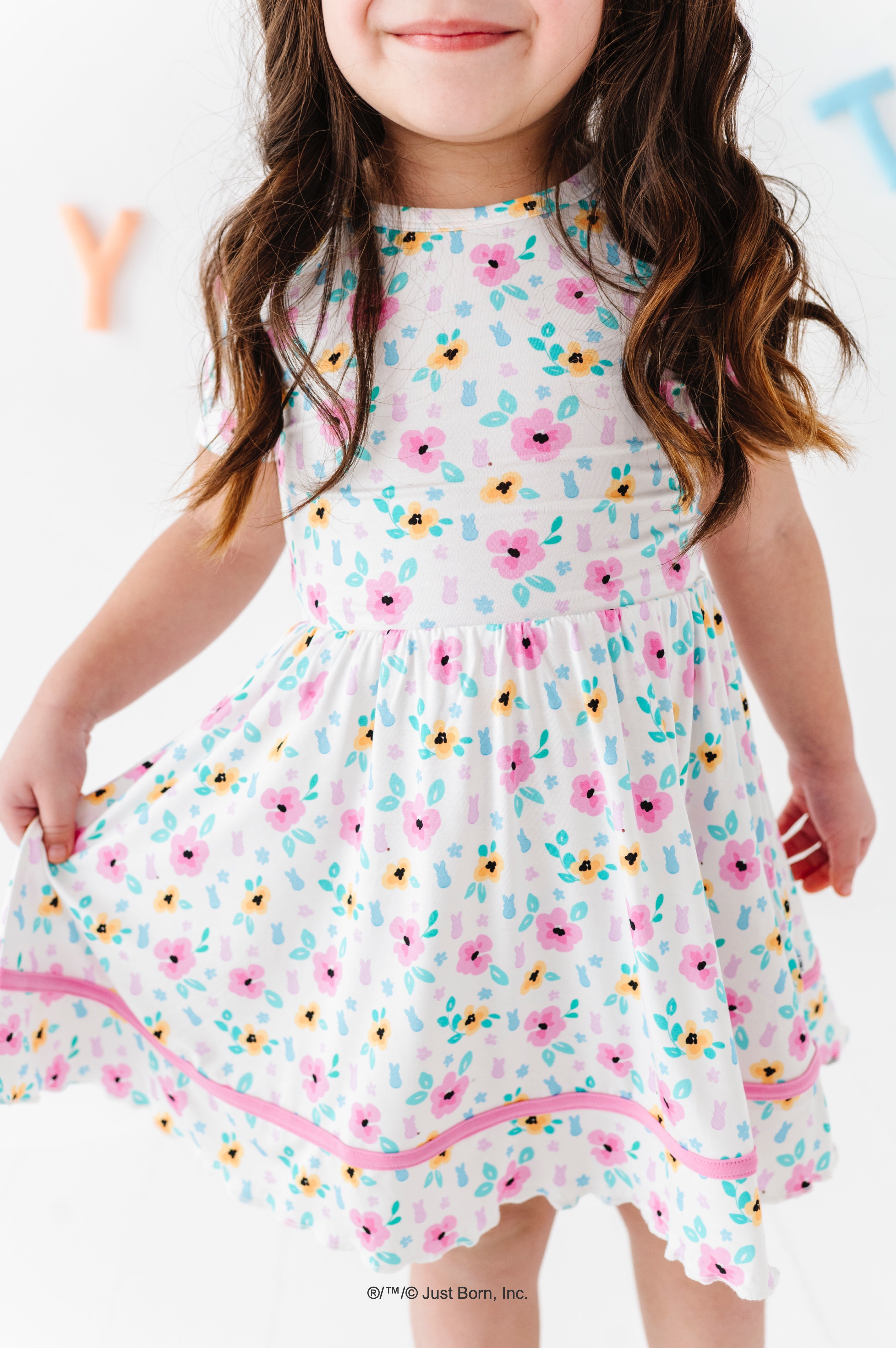 Child wearing a floral PEEPS® dress with a white background